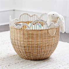 a wicker basket with a stuffed animal in it on a white rug next to a window