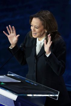 a woman standing at a podium with her hands in the air