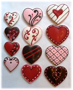 some heart shaped cookies on top of a white table with red and black designs in the middle