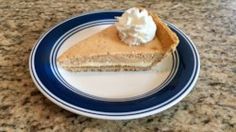 a slice of pie with whipped cream on top sits on a blue and white plate