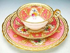 a pink and gold tea set with matching saucers