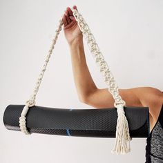 a woman holding a yoga mat with a rope attached to it