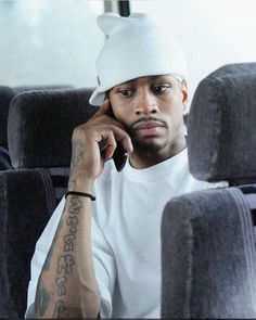 a man sitting on a bus talking on a cell phone while wearing a beanie