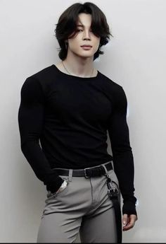 a young man in black shirt and grey pants posing for the camera with his hands on his hips