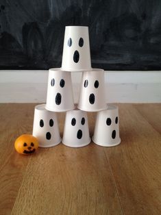 a stack of white cups with black polka dots on them and an orange ball in the middle