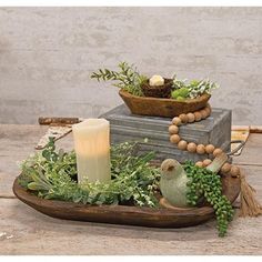 an arrangement of plants and candles on a tray