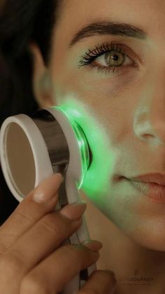 a woman is looking through a magnifying glass with green light on her face