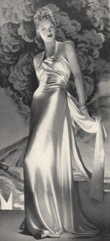 an old fashion photo of a woman in a silver dress with her hands on her hips