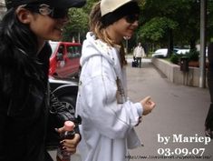 two women standing next to each other on the street talking and smiling at each other