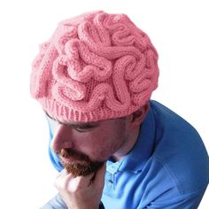 a man wearing a pink knitted hat while holding his hand to his chin and looking at the camera