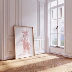 an empty room with a framed ballet poster on the floor and a pair of ballet shoes