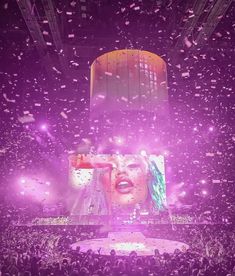 a large crowd at a concert with confetti falling from the ceiling and on to the stage