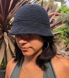 a woman wearing a blue crochet hat next to a plant