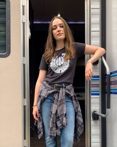 a woman standing in the doorway of a trailer with her hand on her hip and looking off into the distance