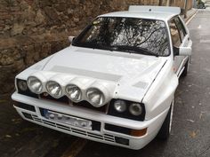 a white car parked next to a stone wall