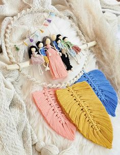 four small dolls are hanging from a string on a white furnishing with beads and tassels