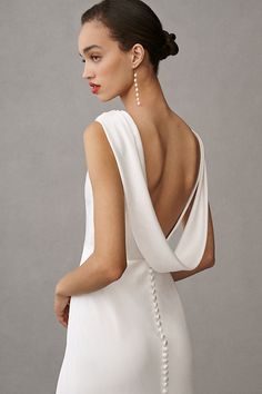 a woman in a white dress with pearls on her neck and back, looking to the side