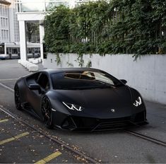 a black sports car is parked on the side of the road next to a building