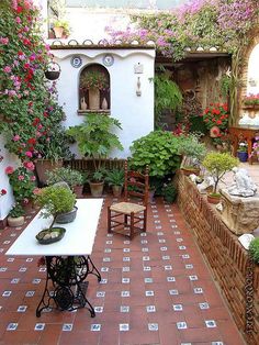 an outdoor dining area with potted plants and flowers on the walls, along with a brick patio