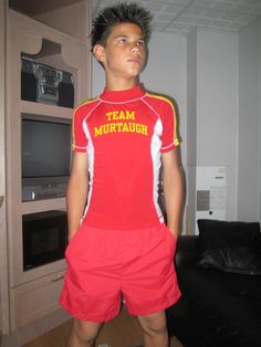 a young man is standing in front of a tv wearing red and yellow soccer uniforms