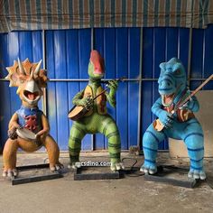 three statues of animals playing instruments in front of a blue wall