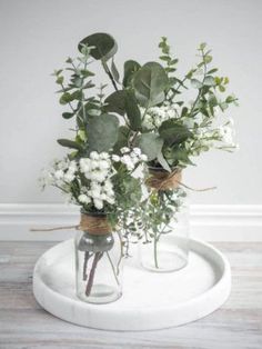 two vases with flowers are sitting on a tray