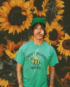 a man standing in front of a bunch of sunflowers wearing a green shirt