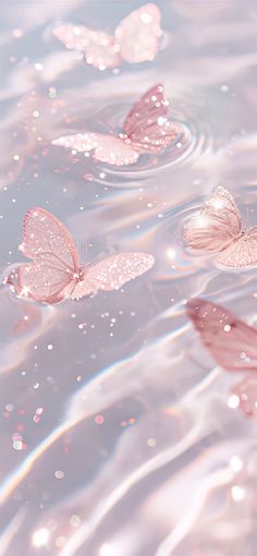 three pink butterflies floating on top of water with bubbles in the air and one flying above them
