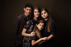 three young people are posing for a photo together in front of a dark background, with one woman holding the other's arm around her neck