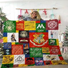 a woman is holding up a quilt with hogwart's crests on it