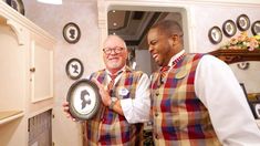 two men standing next to each other in a kitchen holding up a plate with an image on it