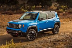 a blue jeep driving down a dirt road