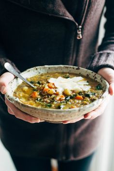 a person holding a bowl of soup in their hands