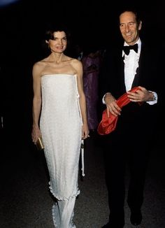 a man in a tuxedo standing next to a woman in a white dress