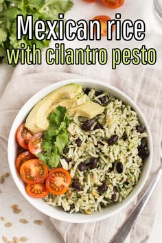 mexican rice with cilantro pesto in a white bowl next to tomatoes and avocado