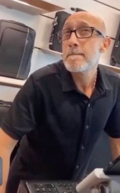 an older man sitting in front of a laptop computer with his hands on the keyboard