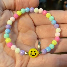 a person holding a bracelet with a smiley face beaded on the front and colorful beads around it