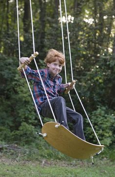 a young boy swinging on a wooden swing