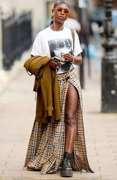 a woman is walking down the street with headphones in her ears and looking at her phone