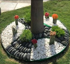 a tree with rocks and flowers around it