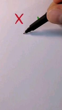 a hand holding a pen over a piece of paper with a cross drawn on it