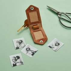 a leather case sitting on top of a table next to some pictures and a pair of scissors