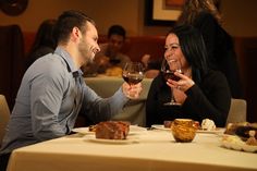 two people sitting at a table drinking wine