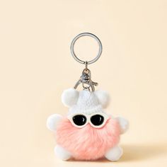 a small stuffed animal with sunglasses on it's face is sitting in front of a keychain