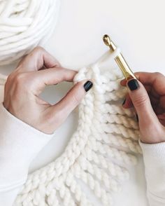 a woman's hand is holding a knitted object