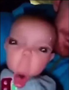 a baby sticking its tongue out while being held up to it's face in the air