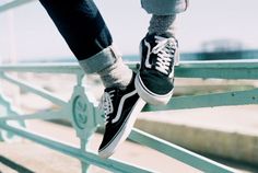 a person wearing black and white shoes standing on a rail