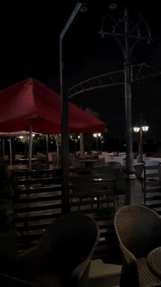 tables and chairs with red umbrellas at night