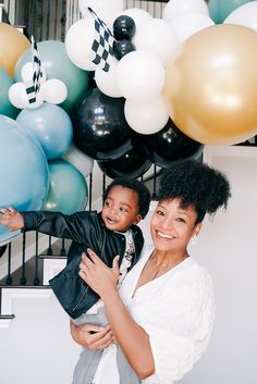 a woman holding a child in front of balloons