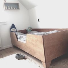 a small child's bed in a room with white walls and wooden flooring